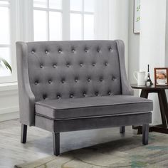 a gray couch sitting on top of a wooden floor next to a table and chair