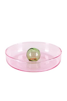 a pink glass bowl with a green ball in the center on a white background,