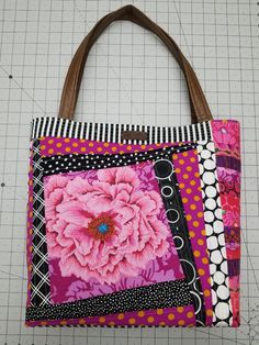 a pink flower is sitting on top of a patchwork tote bag with leather handles