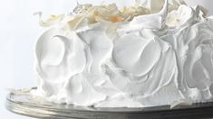 a white frosted cake sitting on top of a metal platter