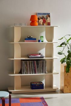 a white shelf with various records on it and a potted plant next to it