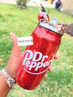 a person holding up a red dr pepper drink in their hand with a tag on it