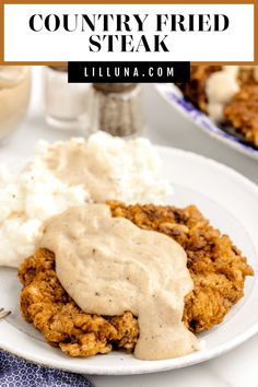 a white plate topped with meat covered in gravy next to mashed potatoes