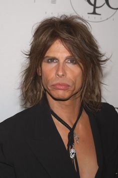 a woman with long hair wearing a black jacket and necklace on her neck is looking at the camera