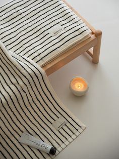 a white candle sitting next to a black and white striped blanket