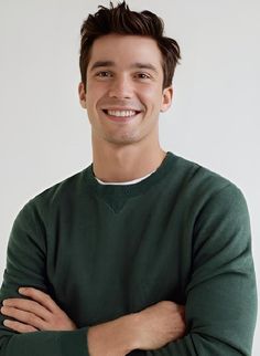 a smiling man in a green sweater with his arms crossed