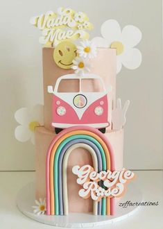 a three tiered cake with a vw bus on top and rainbows in the background