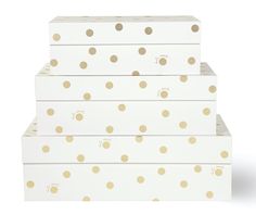 three white boxes with gold polka dots on the top and bottom, stacked up against each other