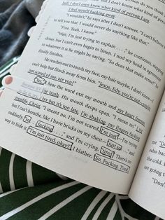 an open book sitting on top of a green and white striped bed sheet with writing