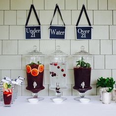 there are four different types of drinks on the table with name tags hanging above them