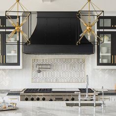 a kitchen with marble counter tops and black cabinets, gold accents on the hoods