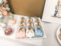 a table topped with cookies and cupcakes next to a framed photo on the wall