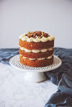 a cake sitting on top of a white plate next to a blue cloth covered table