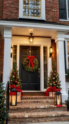 two christmas wreaths on the front steps of a house with red bows and lights