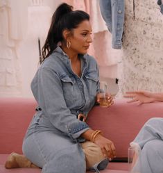 two women sitting on a pink couch talking to each other in front of clothing racks