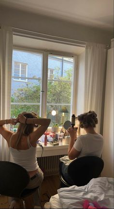 two women sitting at a table in front of a window