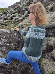 a woman is sitting on some rocks