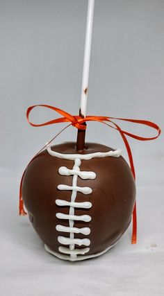 a chocolate covered candy with white and orange stripes on it, tied to a stick