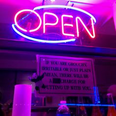 a neon sign that reads open above bottles