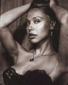 a black and white photo of a woman with her hands on her head, posing for the camera