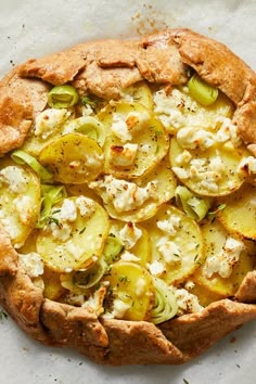 a pizza with cheese and vegetables on it sitting on a piece of parchmented paper