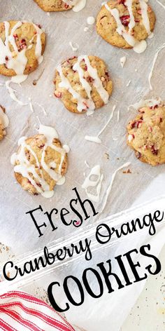 fresh cranberry orange cookies with white icing on a baking sheet and red and white striped napkin