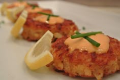 crab cakes with lemon wedges on a white plate