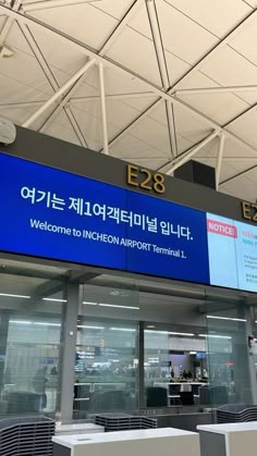 an airport terminal with large blue signs above the doors and tables in front of them