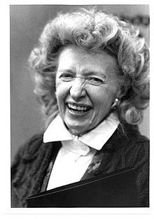 an old photo of a woman smiling and holding a binder in her right hand