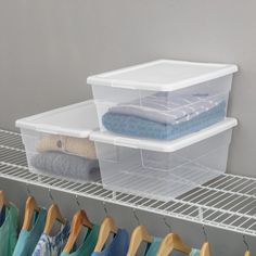 two plastic storage bins with clothes hanging on the rack next to eachother