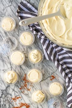 an overhead view of cupcakes with frosting in glass cups on a marble surface