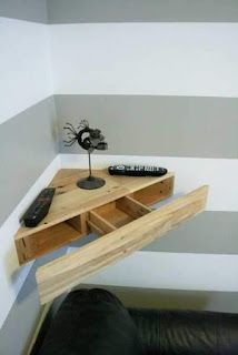 a wooden table with two drawers and a remote control on it in front of a striped wall