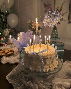 a birthday cake with lit candles sitting on top of a table next to other desserts