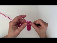 two hands are holding yarn and crochet together to make a heart shaped ornament