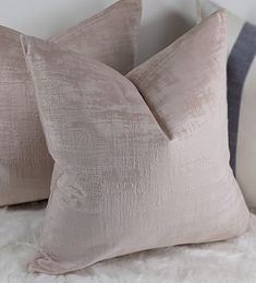 three pillows sitting on top of a white furnishing covered bed next to each other