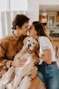 a man and woman kissing while holding a dog