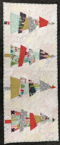 a quilted wall hanging on the side of a black table cloth covered in multicolored fabric