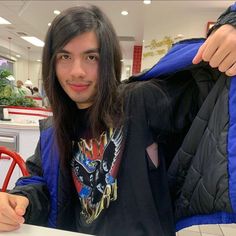 a man with long hair sitting at a table in front of a plate of food