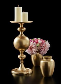 two gold vases with flowers in them on a black table next to each other