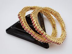 Designer Ruby gold plated bangles are studded with semiprecious stones. Polish and stones are guaranteed. Comes in a pair ( 2 bangles) Jewelry care instructions : 1. Keep jewelry away from direct heat,water,perfumes,deodorants and other strong chemicals. 2. Any moisture or sweat should be properly wiped off before preserving inside.Store it in air tight zip lock bags NOT in velvet box or pouch. Store it in cool, dry place. 3. Your jewelry should be the last thing you put on and the first thing to take off. Imitation jewelry is not meant to last forever, but why not to make it last, as long as you can Designer Bangles, Jewellery Wedding, The Bangles, Bracelets Design, Gold Plated Bangles, Bangles Indian, Jewelry Care Instructions, Indian Wedding Jewelry, Bangle Designs