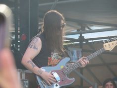 a man with long hair playing a guitar at a music festival in front of an audience