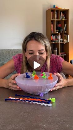 a woman sitting at a table with a cake in front of her and lots of beads on it