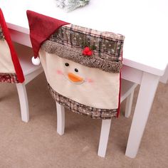 two snowmen sitting on top of white chairs at a table with christmas decorations around them