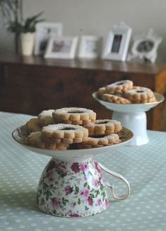 there are some cookies that are on the cake plate and one is sitting on the table