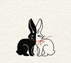 a black and white rabbit with a red ribbon around its neck sitting next to another bunny