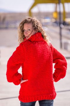 a woman in a red sweater is posing for the camera with her hands on her hips