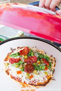 a pizza sitting on top of a white plate covered in toppings next to a pink surfboard