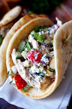 three pita breads filled with chicken salad on top of a white paper towel