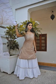 This golden glittery georgette kurta is paired with white sharara pants.  The outfit is completed with a hand crafted gota work net dupatta. White And Gold Sharara, Sharara Designs Party Wear, Gold Sharara, White Gharara, Sarara Dress, Sharara Suit Designs, White Sharara, Dandiya Dress, Indian Fits