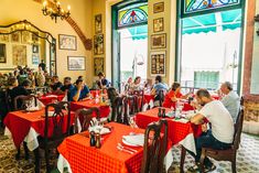 people sitting at tables in a restaurant with red and white tablecloths